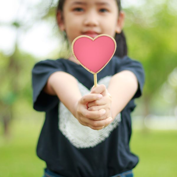 Asian little girl showing wooden sign heart shallow depth of field select focus on hands